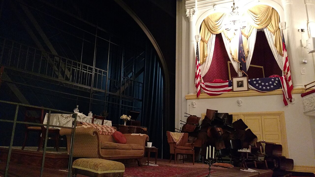 The stage of Ford's Theatre seen past the presidential box, furniture set for a play