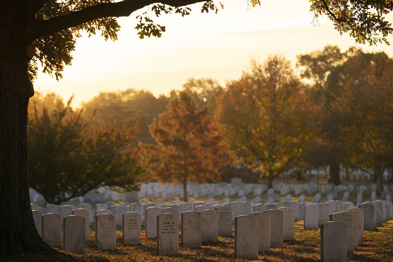 Headstones at Arlington National Cemetery under autumn trees at sunset