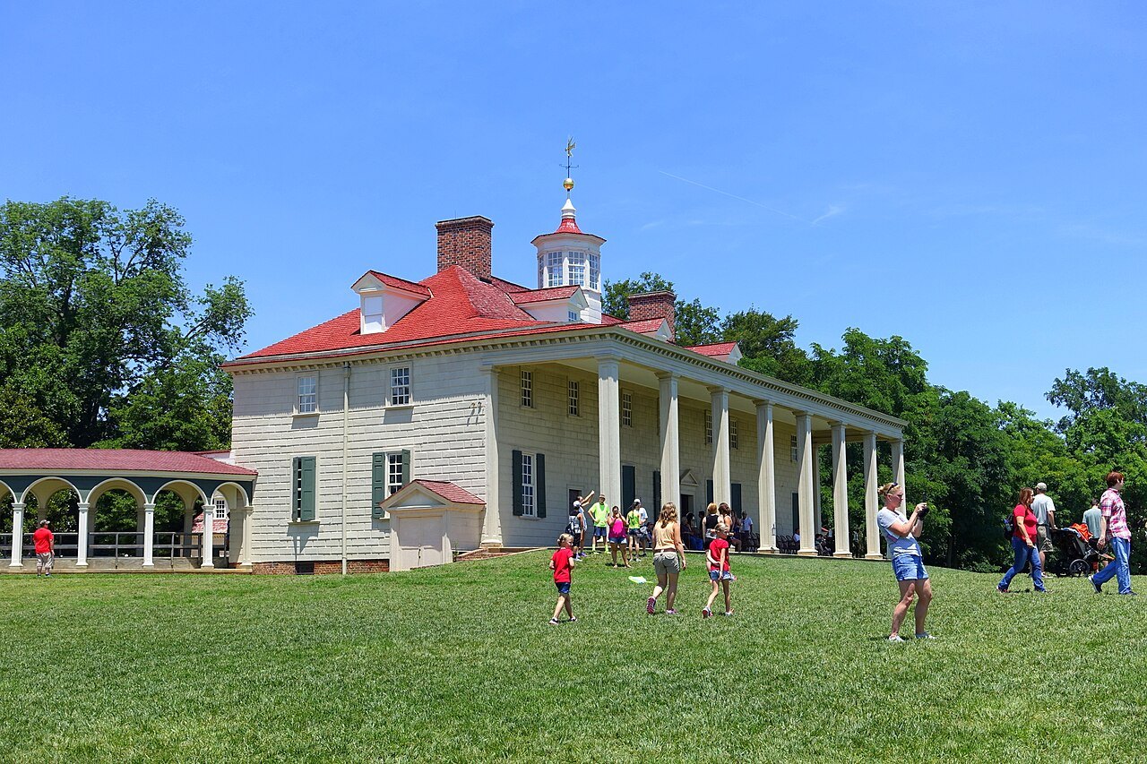 Mount Vernon's long piazza and red roof, visitors on the bowling green