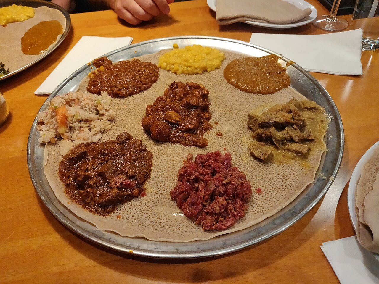 Ethiopian dishes spooned onto injera: lentils, split peas, greens and meat stews