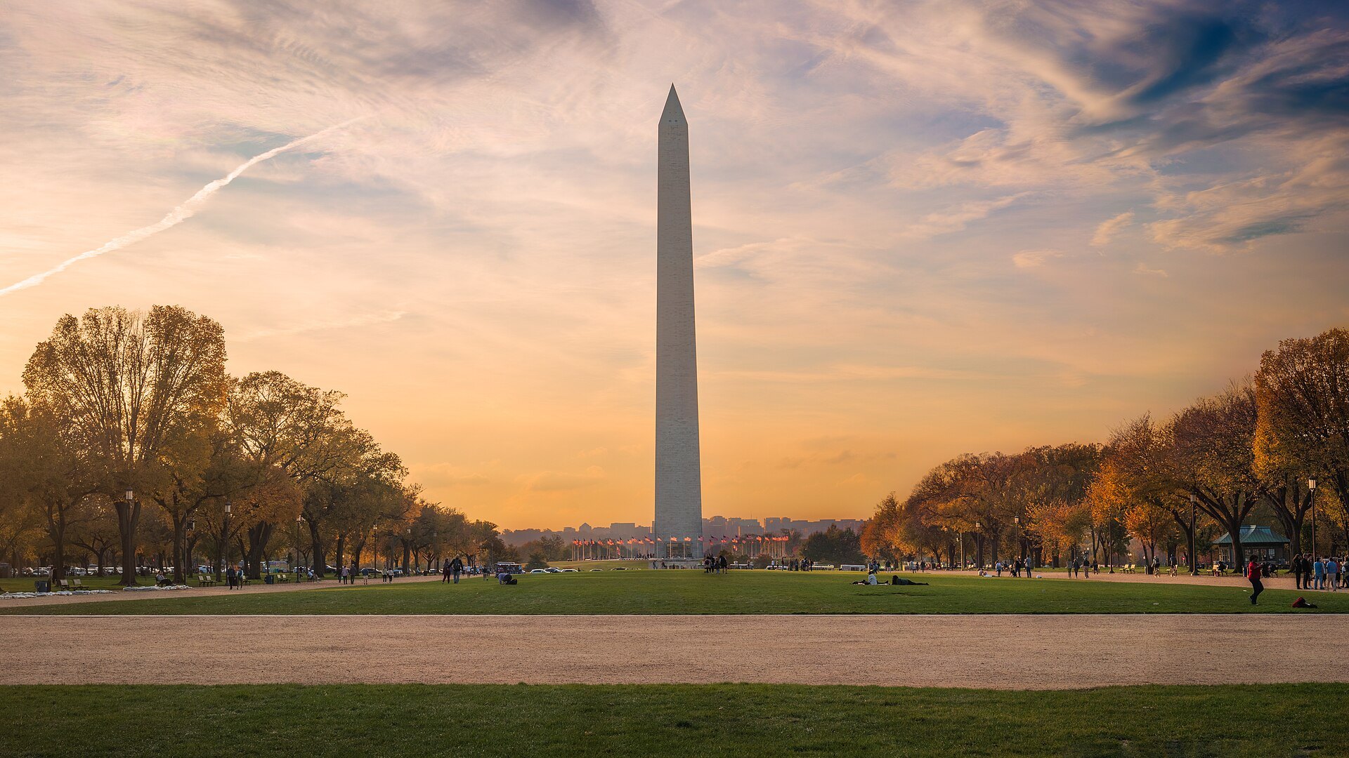The Washington Monument at sunset across the autumn lawn of the Mall