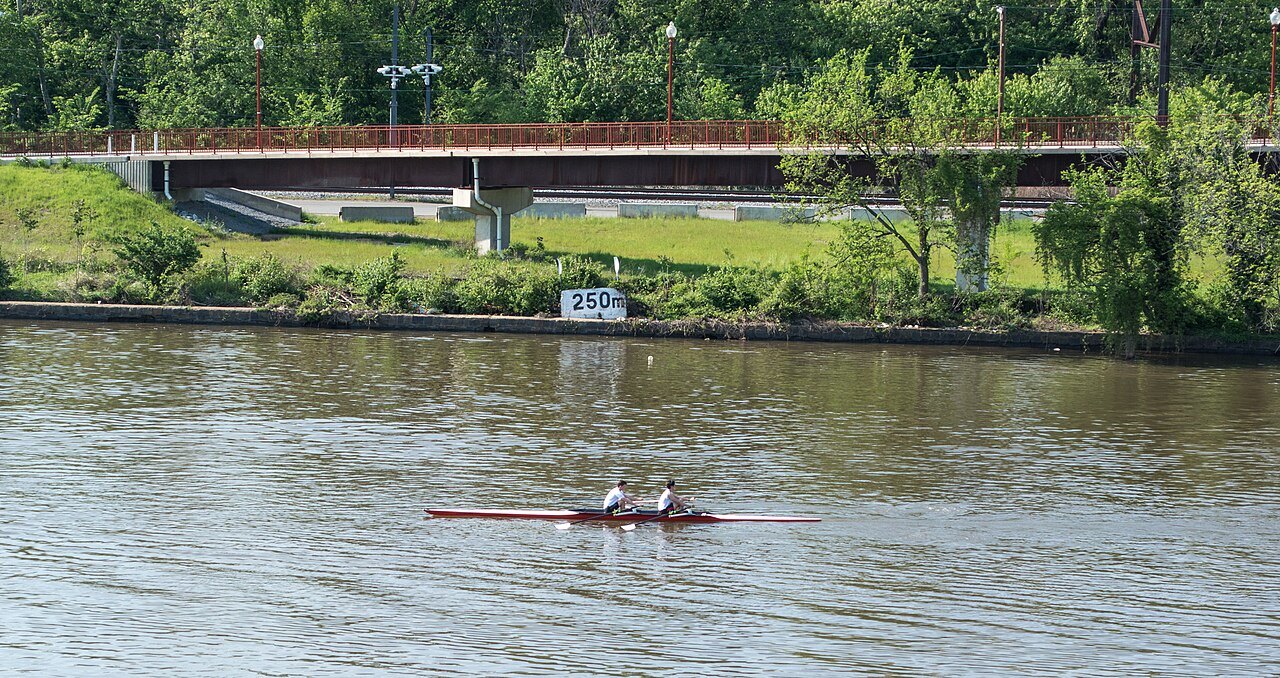 Two rowers on the Anacostia River, the trail's bridge behind them