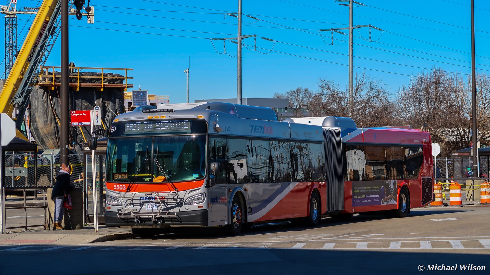 An articulated Metrobus at a stop, the red, white and silver livery