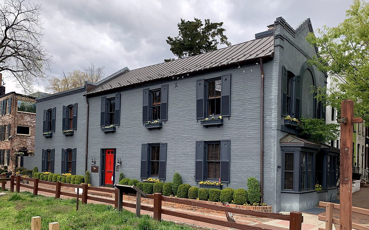 A grey-painted brick house with a red door on Thomas Jefferson Street, Georgetown