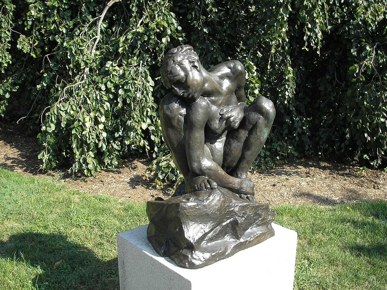 A crouching figure by Auguste Rodin on a plinth in the garden
