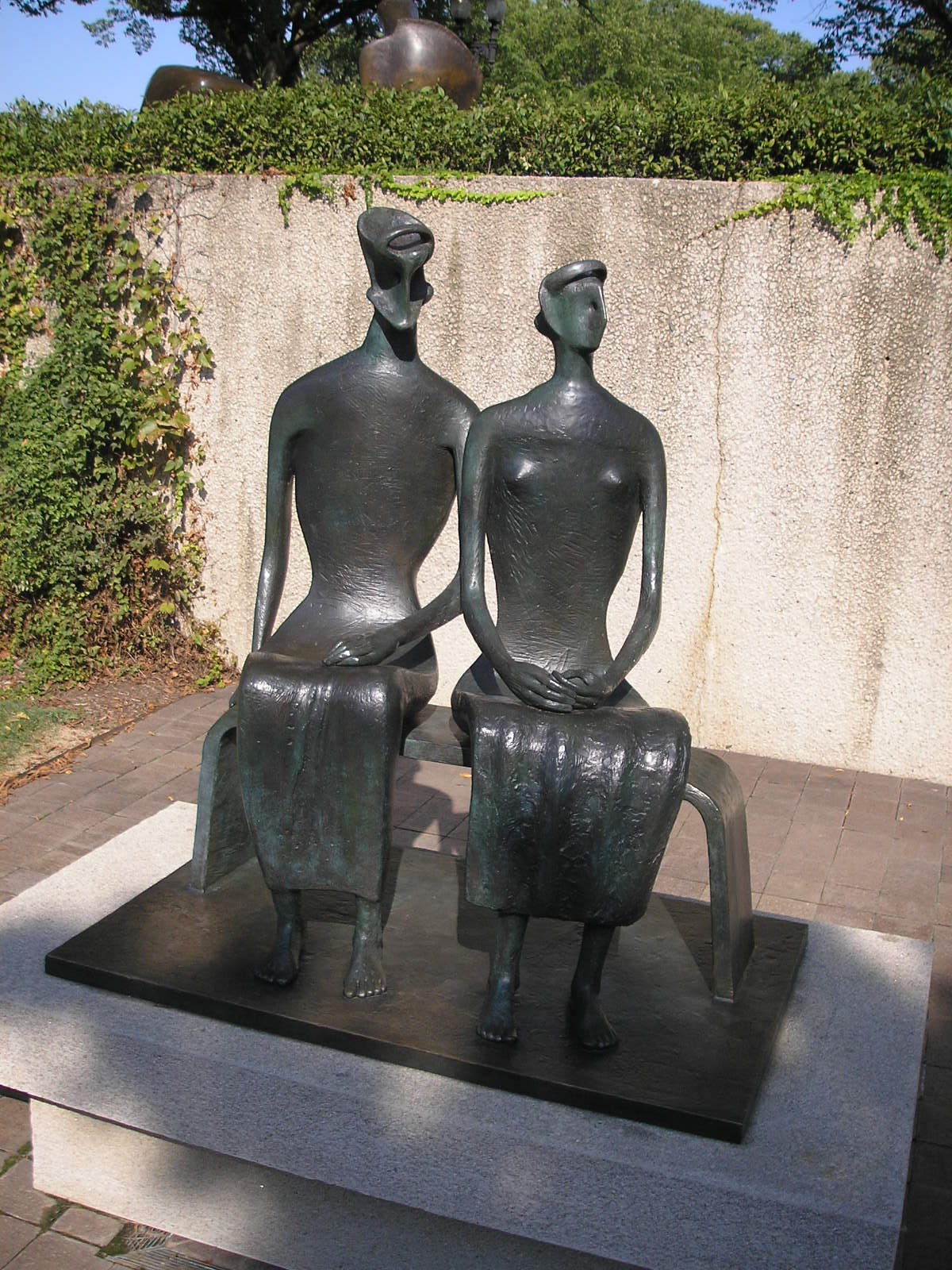 King and Queen, Henry Moore's two seated bronze figures, against a garden wall