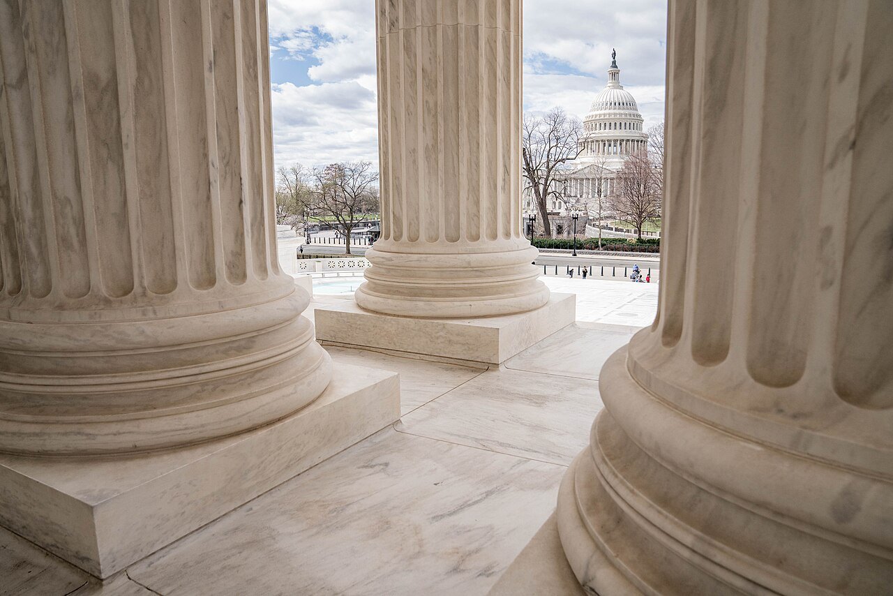 The Capitol dome framed by columns of the Supreme Court's portico