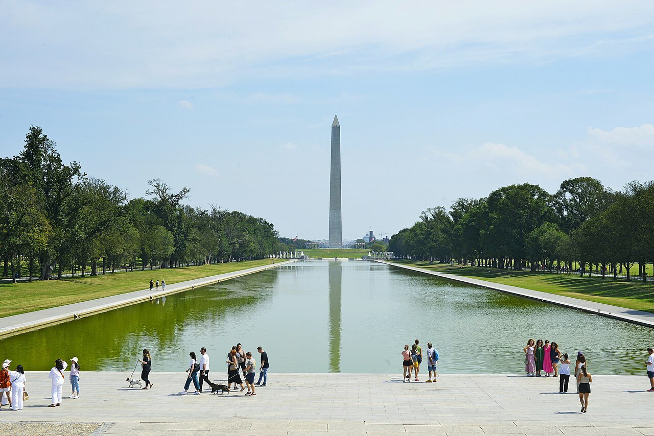 Visitors along the Reflecting Pool, the Monument reflected in the water