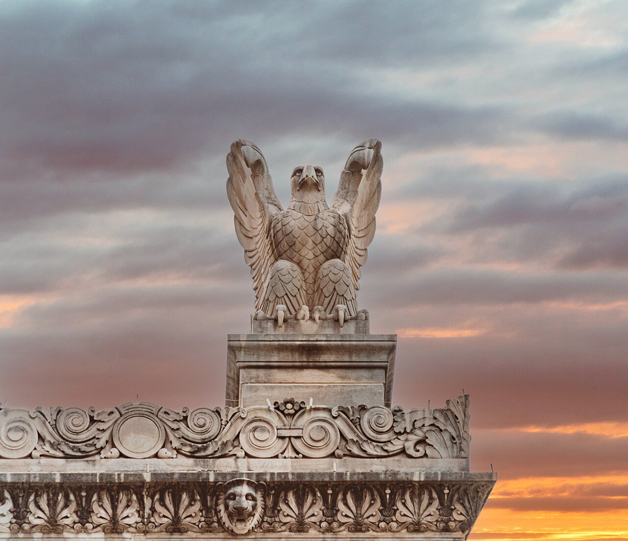 A carved eagle on the Archives Building's parapet against an evening sky