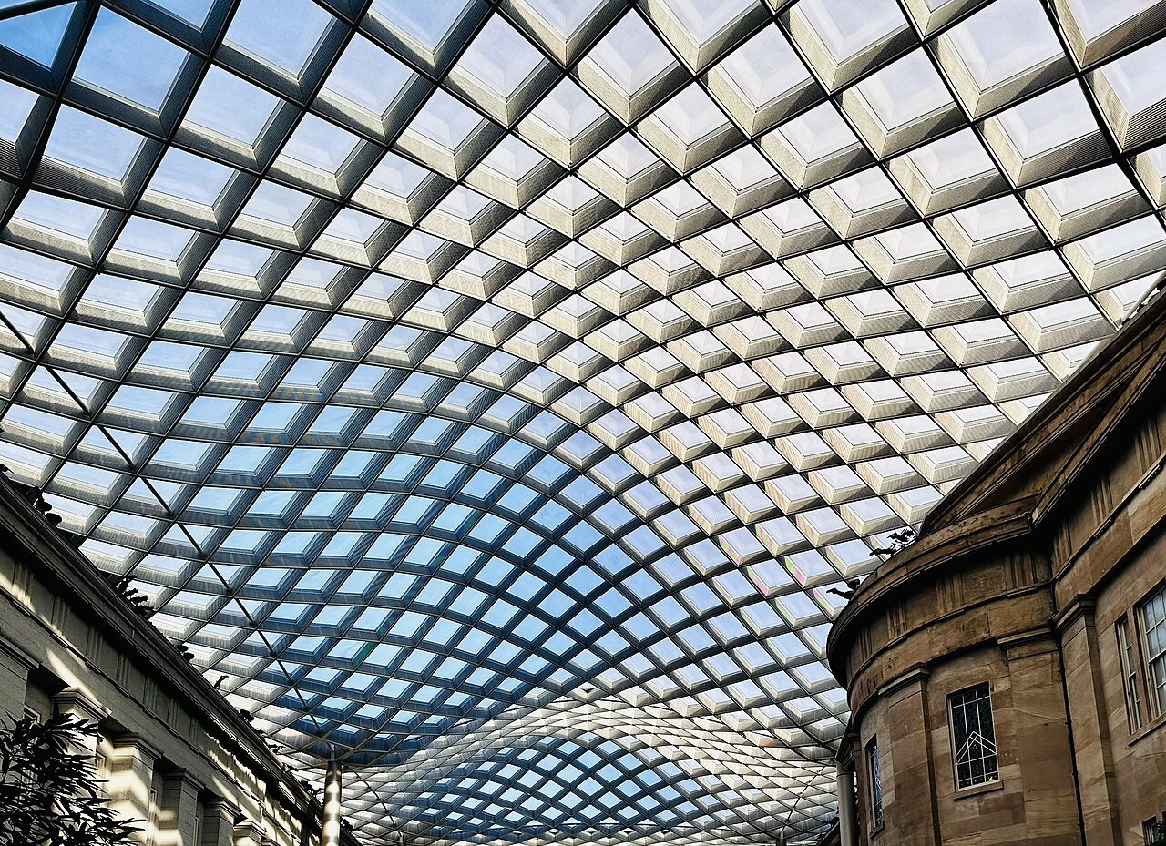 The glass and steel grid of the Kogod Courtyard's canopy, the old building's wall below