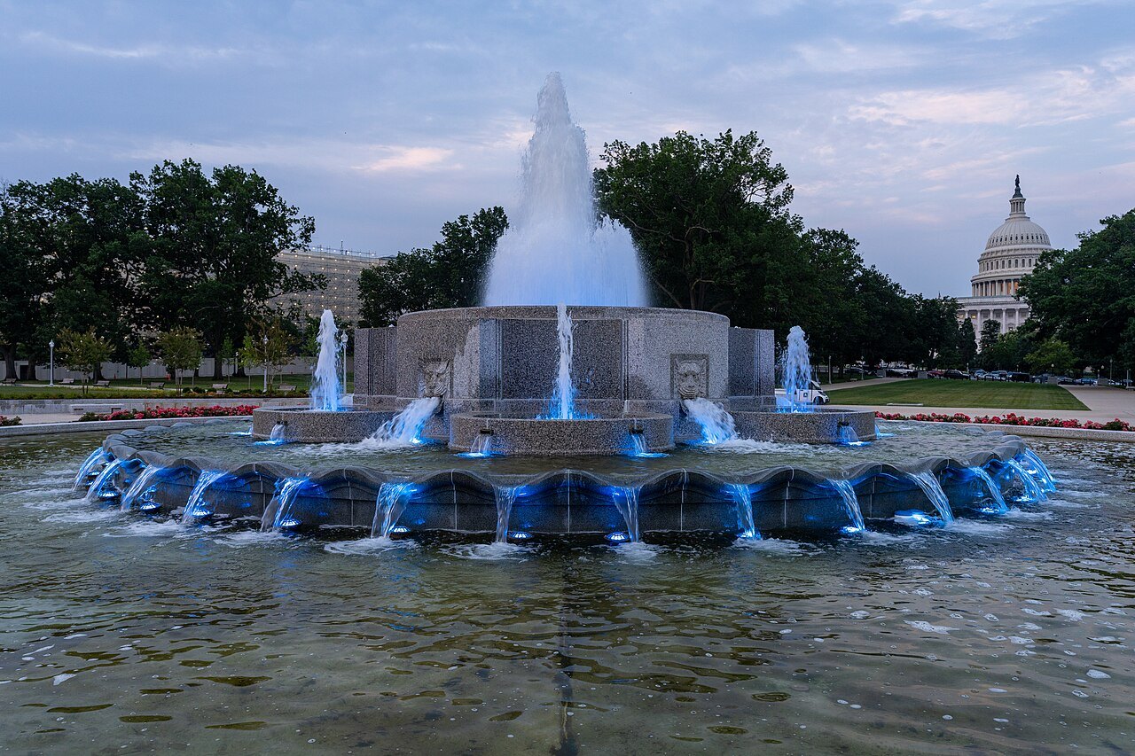 The Senate Fountain lit blue at dusk, the Capitol dome behind