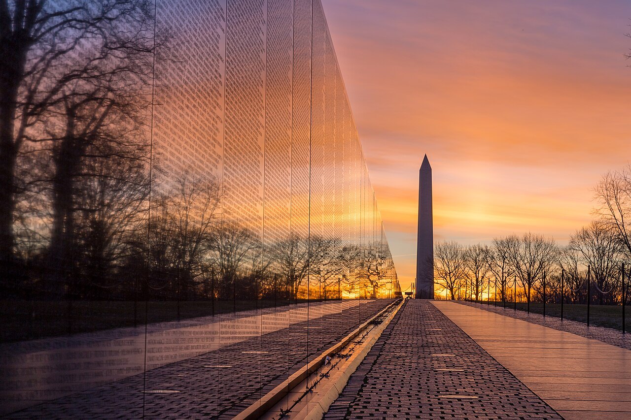 The Monument reflected in the Vietnam Veterans Memorial's black granite wall at sunrise